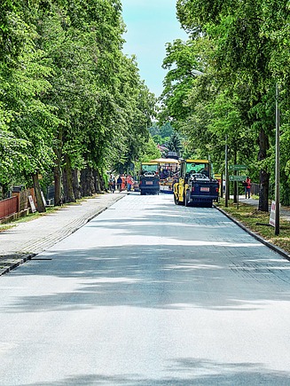 In einer Allee wird ClAir® Asphalt eingebaut.