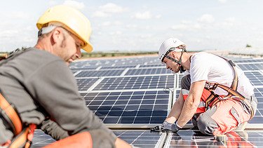 Fotó két építőmunkásról, akik fotovoltaikus rendszert telepítenek