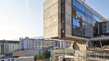 Auskragender Gebäudeteil des RAIQA-Quartiers während der Bauarbeiten mit Blick über Innsbruck.
