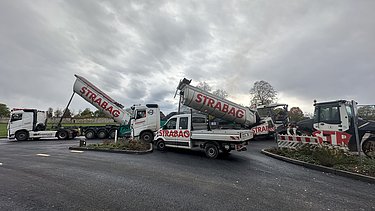 Obrázek asfaltérů přivážejících recyklovaný asfalt na staveniště