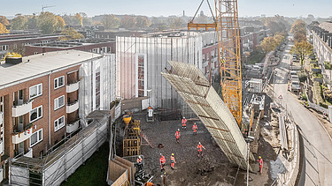 Großer Kran hebt Bauteil auf der U5-Baustelle in einem Wohngebiet in Hamburg