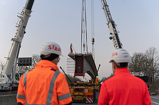 Einheben eines vorgefertigten Brückenträgers per Kran auf der Autobahnbaustelle