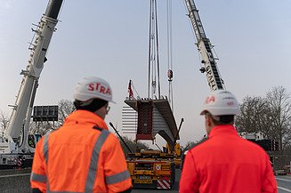 Lifting a prefabricated bridge girder by crane on the motorway construction site