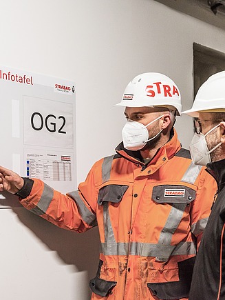 Two employees in front of the LEAN information board.