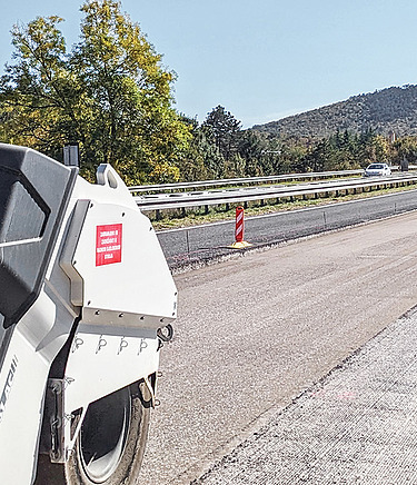 STRABAG henger hideg újrahasznosításos útfelújítás közben, a háttérben egyéb gépek.
