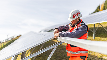 Stavební dělník montuje solární modul ve fotovoltaickém parku Ratten Fotografie stavebního dělníka při montáži solárního modulu v PV-Parku Ratten