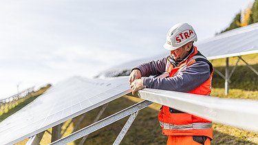 Építőmunkás napelemet szerel a ratteni PV-parkban Fotó egy építőmunkásról, amint napelemet szerel a PV-Park Rattenben