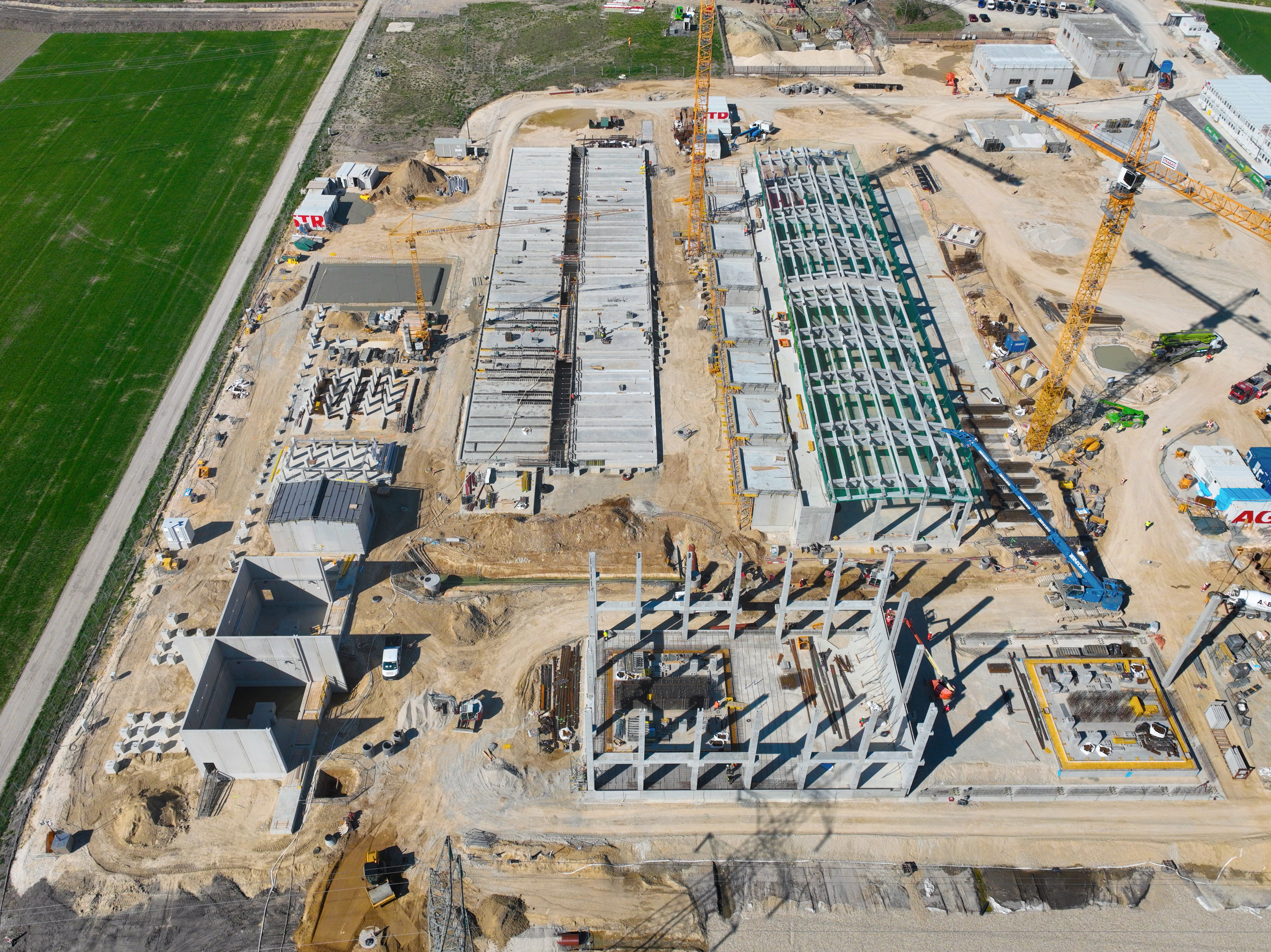 Aerial view of the construction site of an electrolysis plant, showing cranes and the building shell, in Bruck an der Leitha