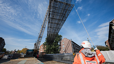 Worker instructing steel construction being lifted by a crane on the U5 construction site in Hamburg