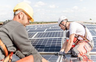 Fotografie dvou stavebních dělníků instalujících fotovoltaický systém