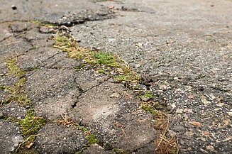 Popraskaná a poškozená asfaltová silnice před renovací