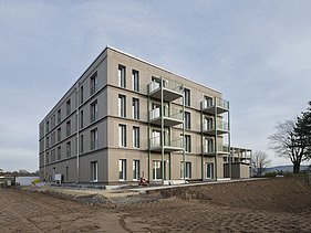 A building complex constructed using a modular timber-frame system, viewed from the outside during the construction phase