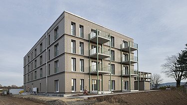 A building complex constructed using a modular timber-frame system, viewed from the outside during the construction phase