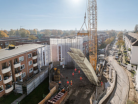 Großer Kran hebt Bauteil auf der U5-Baustelle in einem Wohngebiet in Hamburg