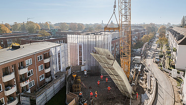 Großer Kran hebt Bauteil auf der U5-Baustelle in einem Wohngebiet in Hamburg