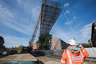 Arbeiter weist Stahlkonstruktion ein, die von einem Kran auf der U5-Baustelle in Hamburg gehoben wird