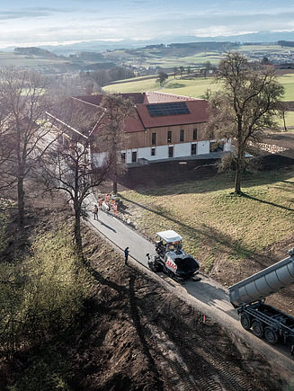 Ein LKW kippt Asphalt mit hohem Recycling-Anteil auf die Baustelle.