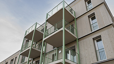 Photo of a multi-story residential building constructed using serial timber construction with green balcony structures