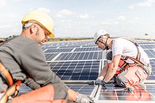 Fotografia dvoch stavebných robotníkov, ktorí montujú fotovoltaické pole